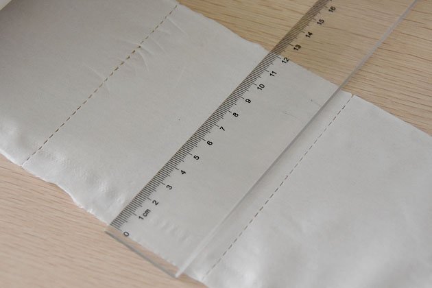 Toilet paper sheet laid flat with a ruler showing the perforation tear line