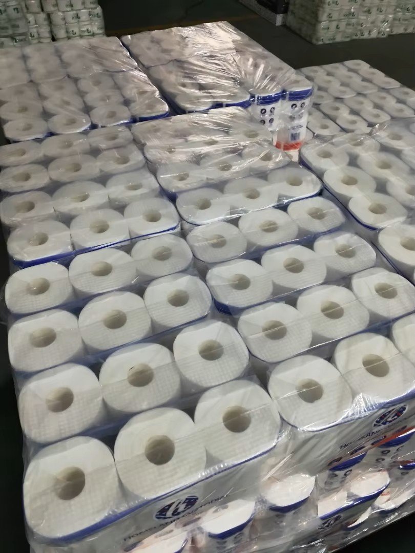 Bulk shrink-wrapped packs of virgin pulp toilet paper rolls stacked in the warehouse